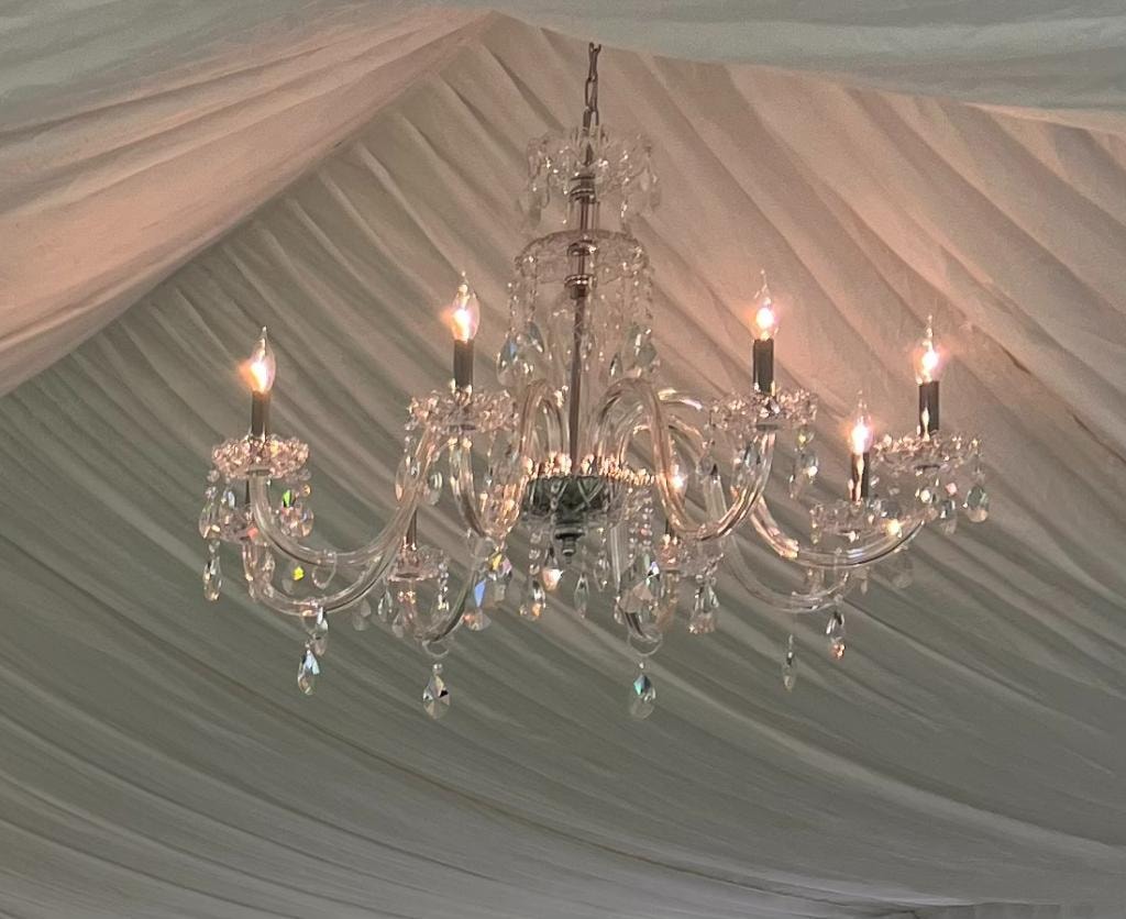 Crystal chandelier hanging from draped tent ceiling