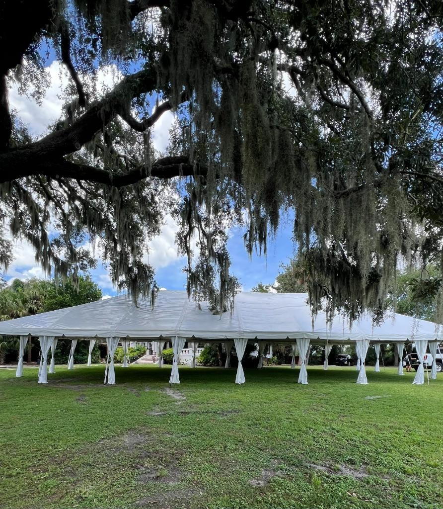 White tent with leg drapes under Spanish moss trees